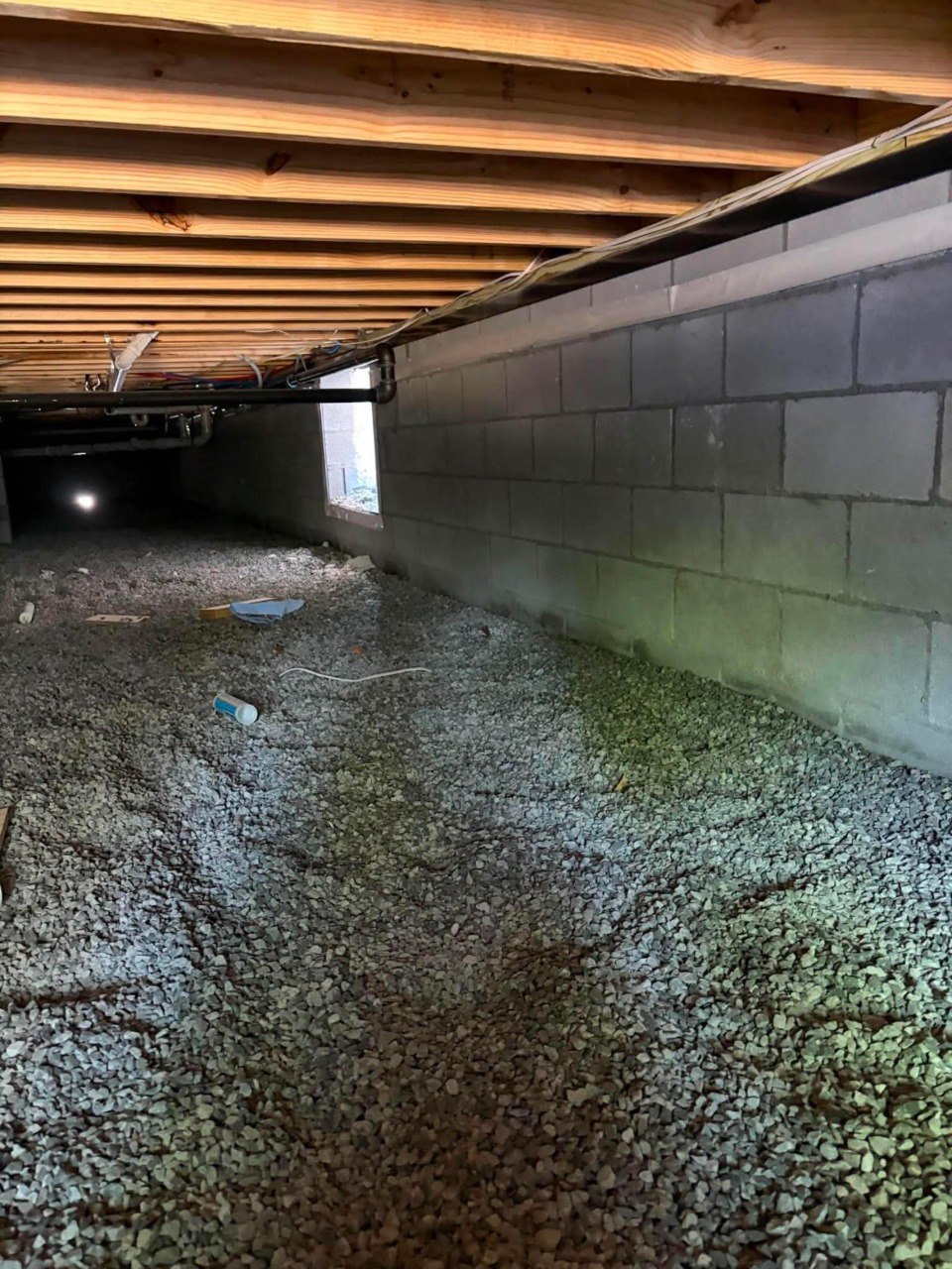 Crawl space with standing water and wet ground before encapsulation